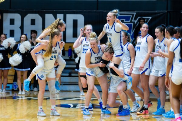 A college women's basketball team celebrate together. 