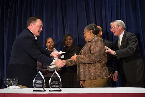 Michael Price, chairman and CEO of Mercantile Bank, presents Arnie Smithalexander with a check for Grand Valley's Upward Bound program. At right is Grand Rapids Mayor George Heartwell.