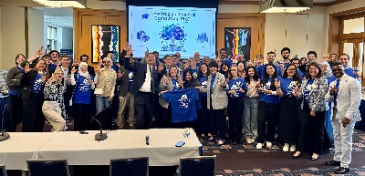 Students and GVSU leaders pose in front of screen raising the "Anchor Up" hand gesture.