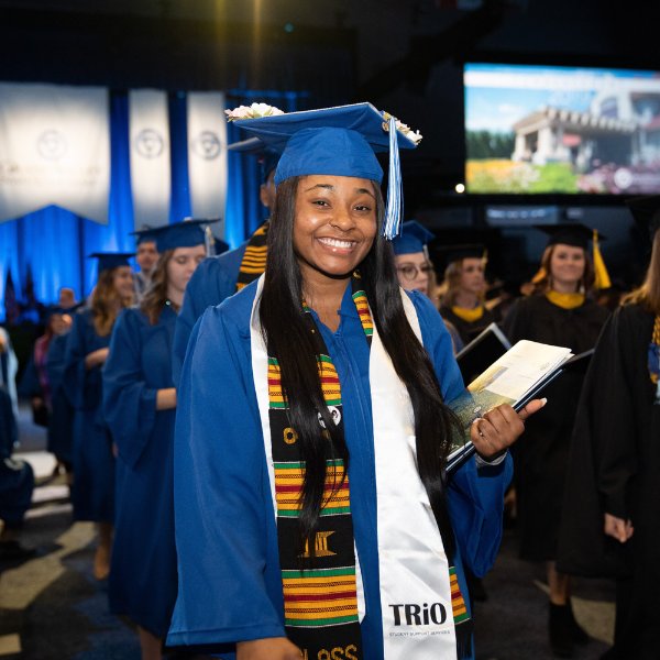 a 2019 graduate pictured at commencement with a TRIO stole, cap and gown