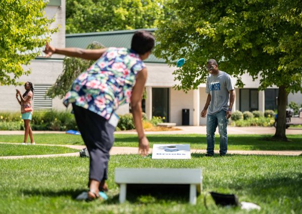 two people play cornhole outside