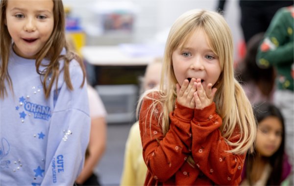 Jayla Tatlock, a second grade student at Vanderbilt Charter Academy, right, reacts with classmates as a stuffed animal and book were given out by Priority Health as part of the Priority Pups program. The program was started by Priority Health to address student mental health.