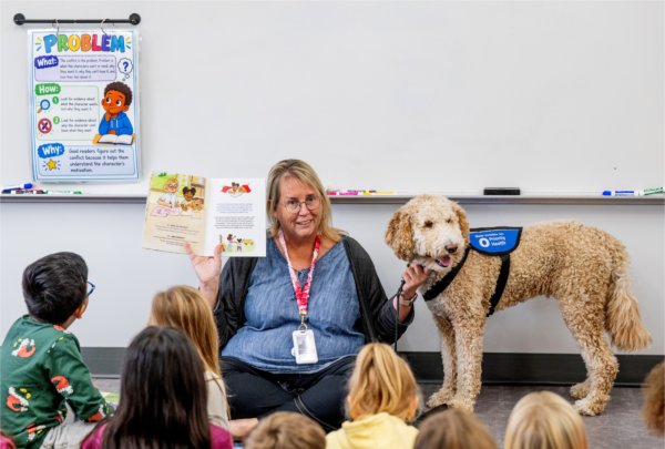 Jasper, a goldendoodle therapy dog, listens to a story with host and 7th grade teacher, Carrie Pifer, at Vanderbilt Charter Academy.