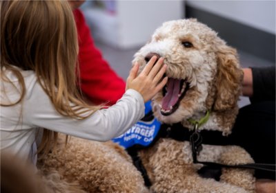 Second grader Leanna Oleniczak touches the nose of Jasper, a goldendoodle therapy dog, after reading time at Vanderbilt Charter Academy. 