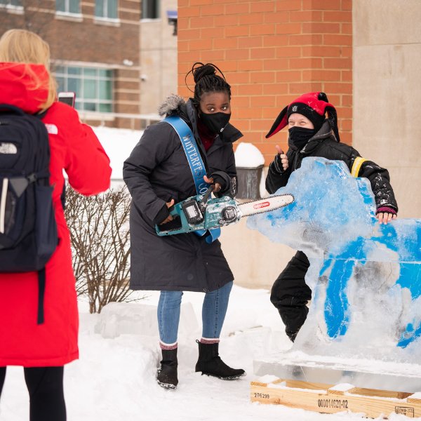 A student poses with an ice sculpture of Michigan and the Great Lakes during GVSU Winterfest activities.