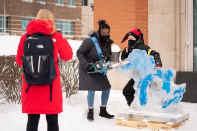 A student has their photo taken with an ice carving of Michigan and the Great Lakes during Winterfest on the GVSU Allendale Campus 