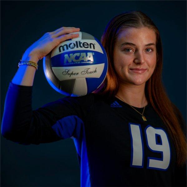 Gabby Orlet, a Grand Valley State volleyball player wearing jersey No. 19, poses with a volleyball resting on her right shoulder with her right hand holding it in place.