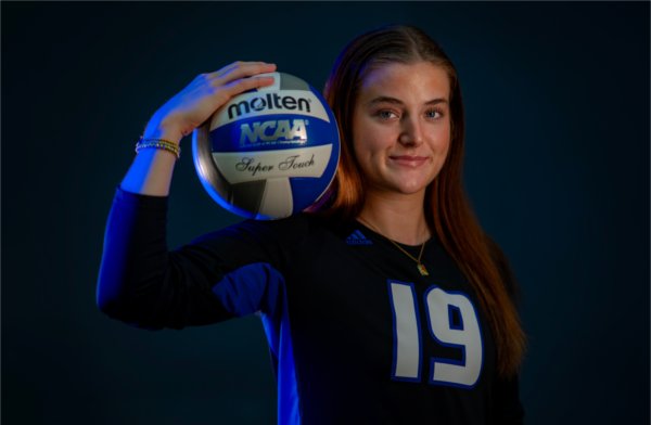 Gabby Orlet poses for a photo wearing her Grand Valley jersey and holding a volleyball on her shoulder with her hand.
