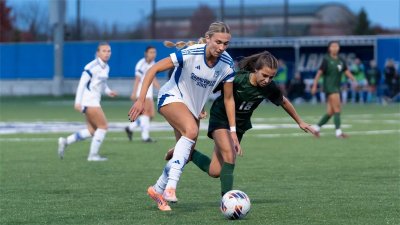 A GVSU soccer player fights for possession of the ball with a Roosevelt player. 