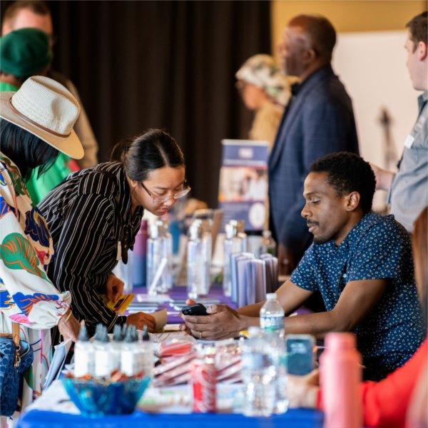 A vendor assists an attendee during a small business fair in Grand Rapids.