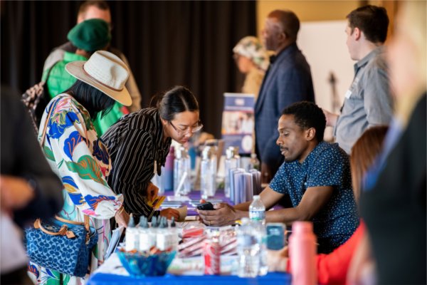 A vendor assists an attendee during a resource fair for small business owners. 