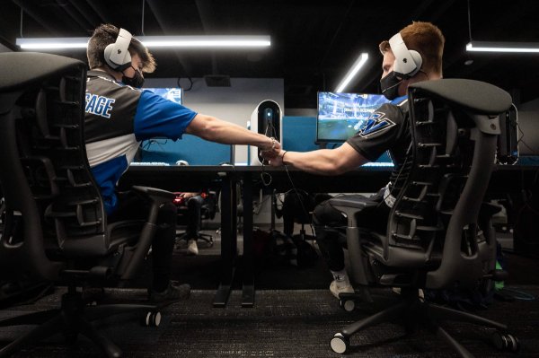  Two students fist bump while sitting at their computers during a Esports tournament. 