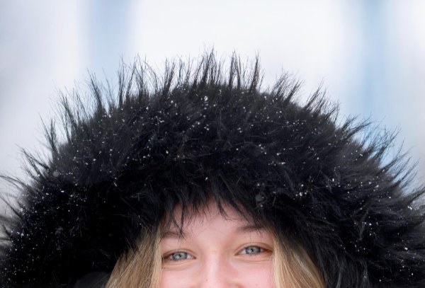 A close-up of a college student's eyes while wearing a snow-covered hooded coat. 