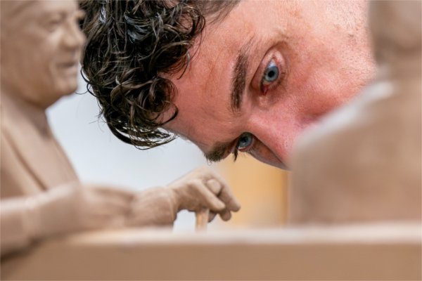 A closeup of a person working on a scale model of a sculpture.