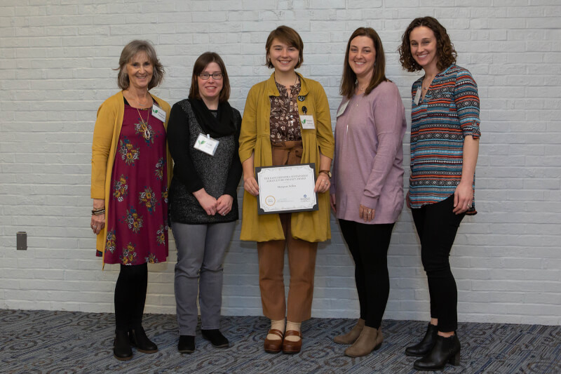 group of women, one in center holding certificate
