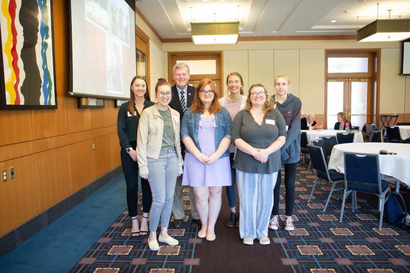 group photo of six women standing in two rows with President Haas