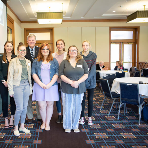 group photo of six women standing in two rows with President Haas