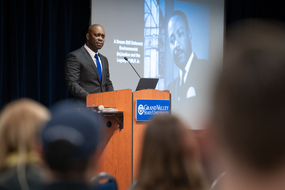 man at podium, with presentation screens showing Dr. King