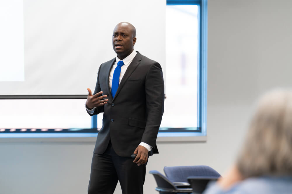 man walking in front of room, giving presentation