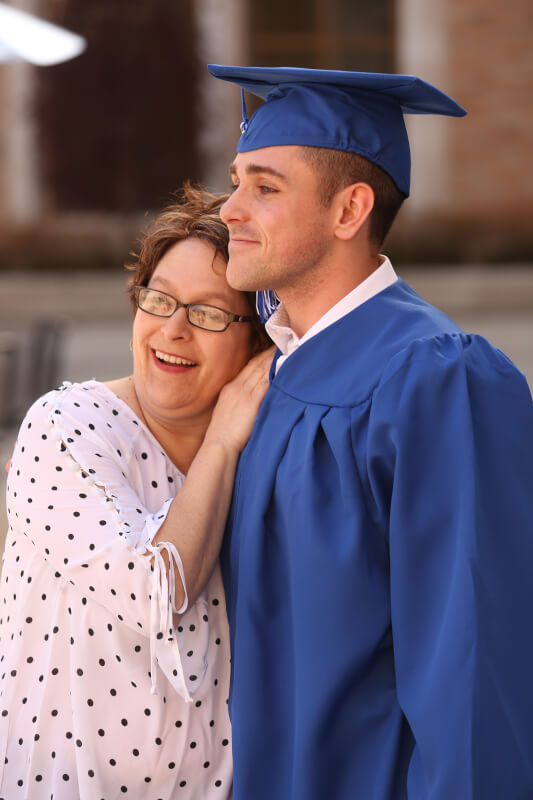graduating student and family outside arena