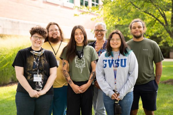 six people standing in two rows outside on the Allendale Campus