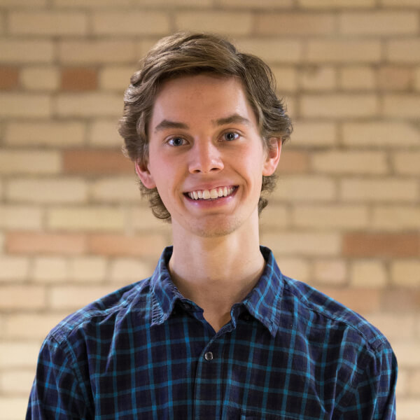 Jordan Vanderham poses for a photo in front of a brick wall.
