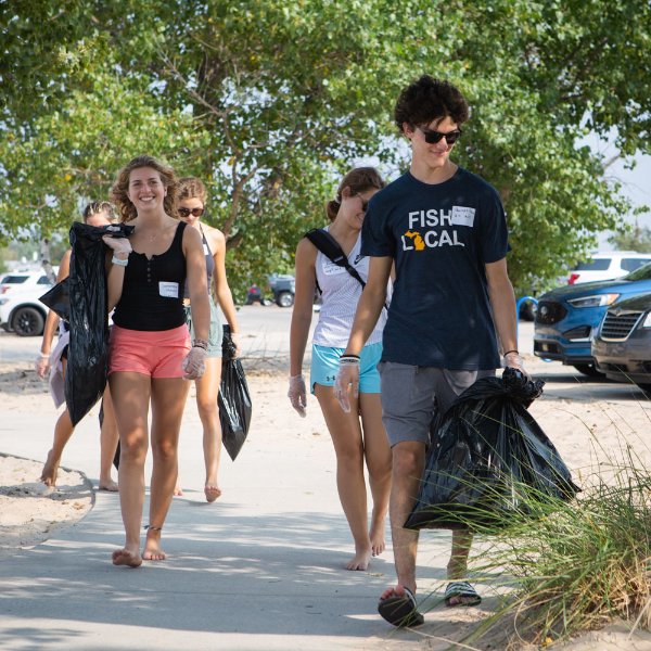 Students walk through park picking up trash.