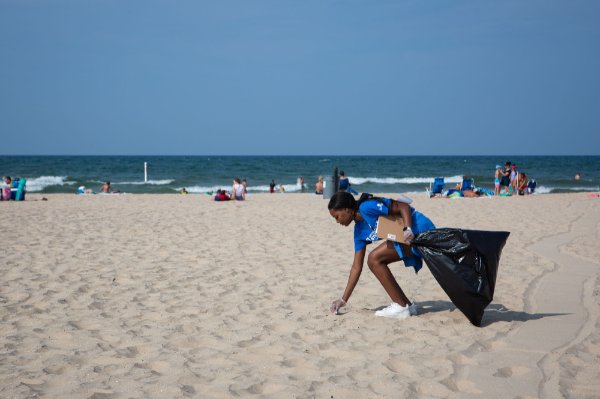 Student picks up trash on beach.