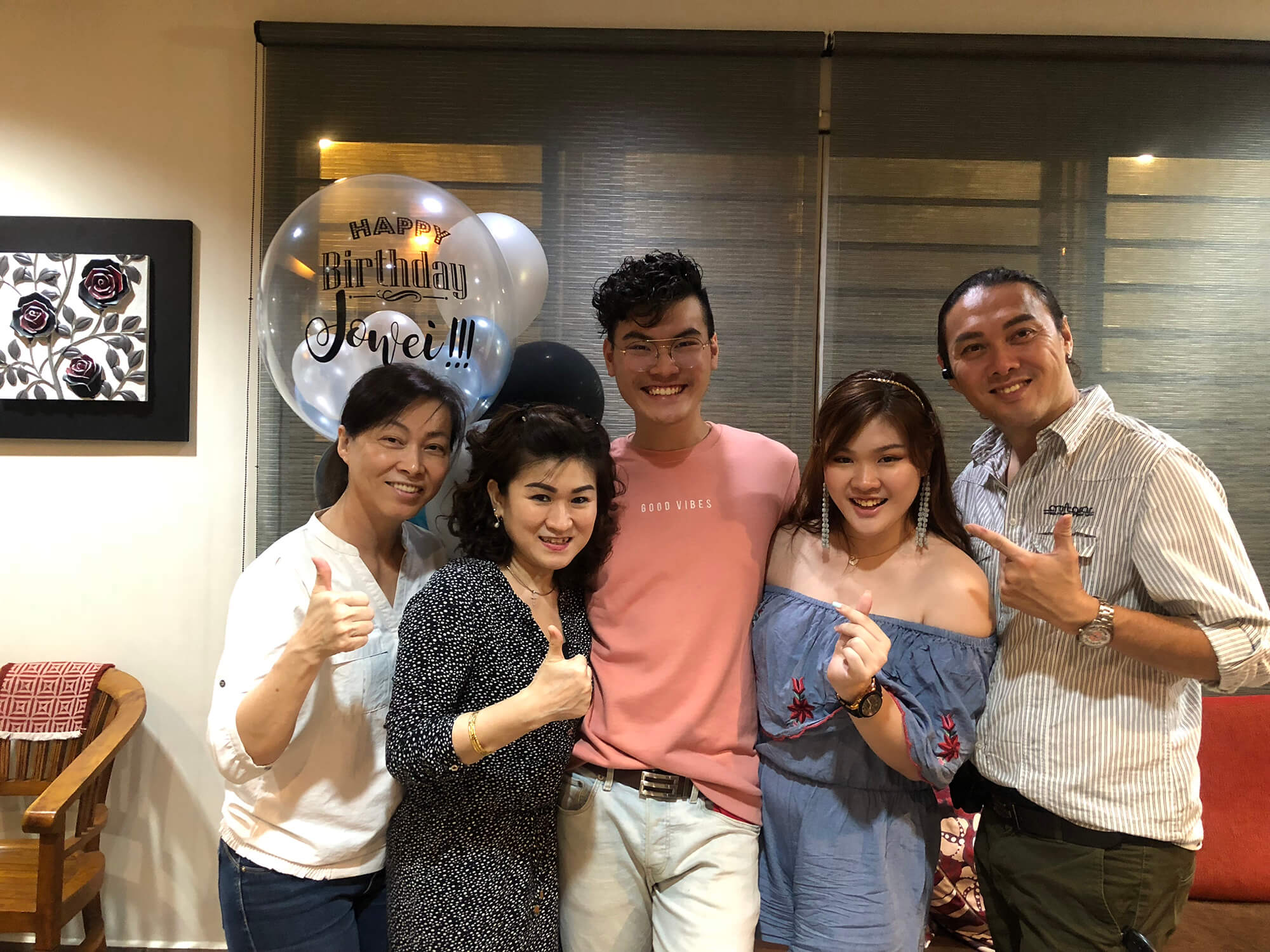 group of people posing with balloons in a home
