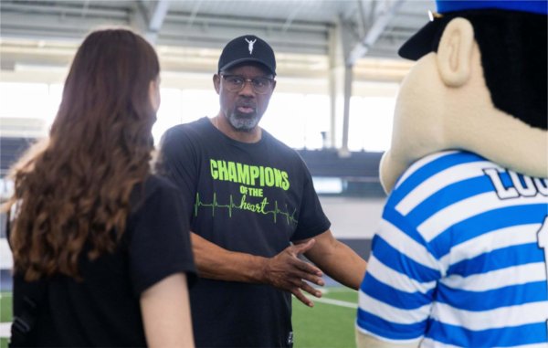 Two people talk at the event with Louie looking on.