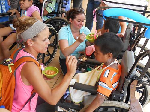 Grand Valley students feed children in Guatemala during one of the seven clinic days of a service-learning trip.