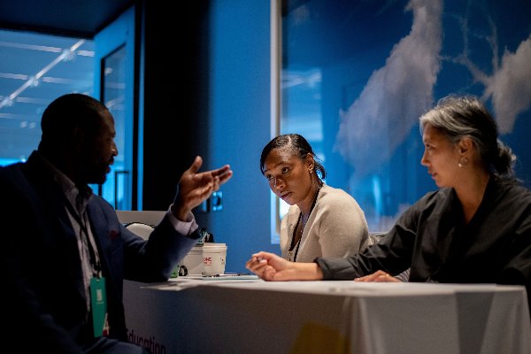 Three people sit at a table and have an intense discussion. 