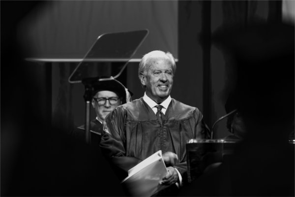  A smiling person holds papers as they prepare to give a speech during Commencement. 