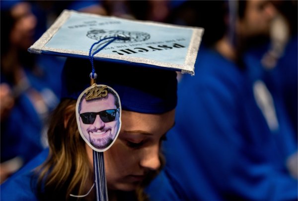  A cutout of a person&#8217;s face wearing sunglasses hangs from a tassel at graduation. 