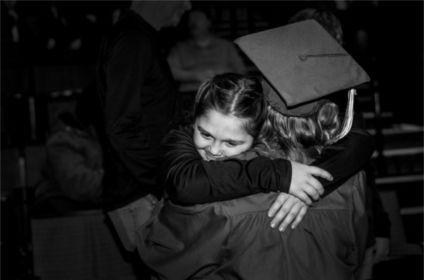  A small child hugs a college graduate in a cap and gown. 