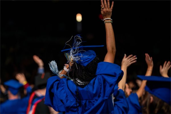 A graduate waves to family as their tassel moves in the air. 