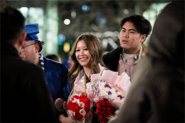 A person smiles while holding several bouquets of flowers.