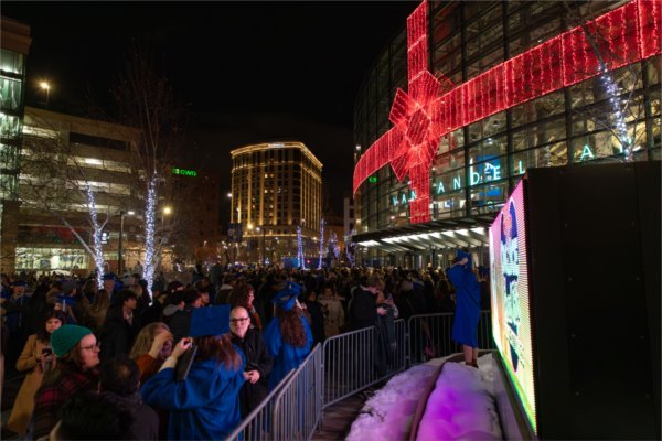  A large crowd of graduates find their family members and supporters after leaving an arena at night. 