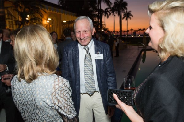 Dave Mehney in open suit jacket talking to woman with back to camera