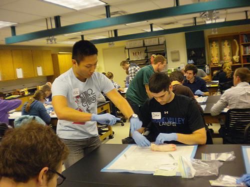 Alex Brennar, left, gives Andrew Grozenski instructions during a suture clinic at the Michigan State University College of Human Medicine.