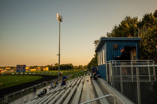 football stadium, man with computer up in stands recording high school game