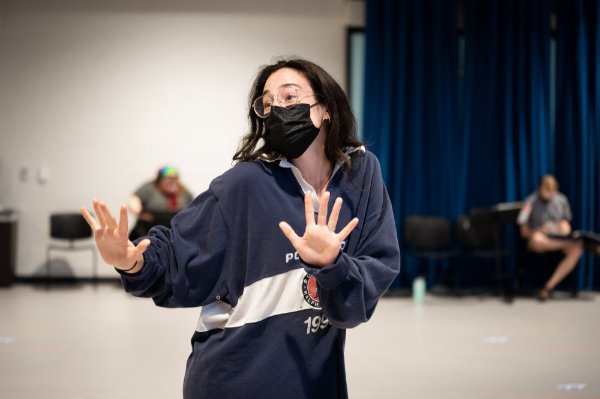 A performer gestures with outstretched hands while singing.