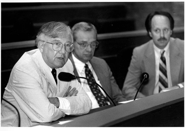 In a black and white photo, Arend D. Lubbers speaks while Glenn Niemeyer and Matthew McLogan look on.
