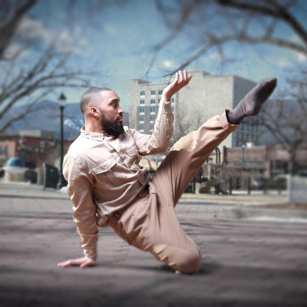 A dancer balances on one knee with one hand on the ground while extending the other leg and arm.