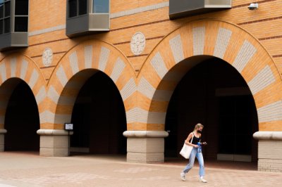 A student, wearing a mask, walks through campus