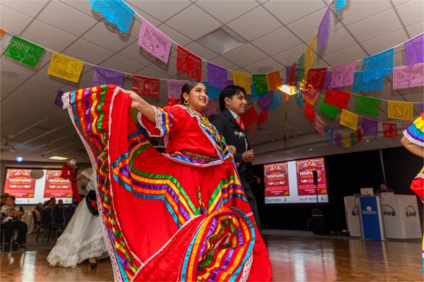 colorful Hispanic dress, escorted by student in suit