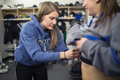Karyn Schmaltz places a heart rate monitor on a women's hockey player at Georgetown Ice Arena. Schamltz's research, with biomedical sciences faculty member Cara Ocobock, measures the energy expenditure of players during a game. Photo by Jess Weal   