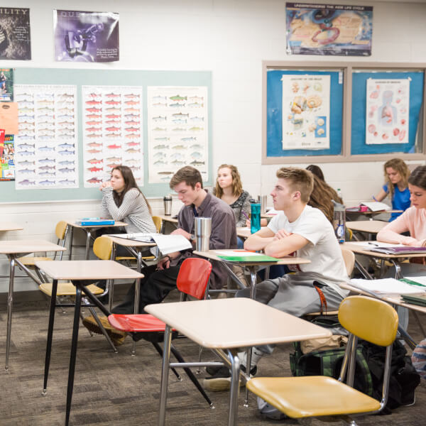Male instructor leading class of students in desks.