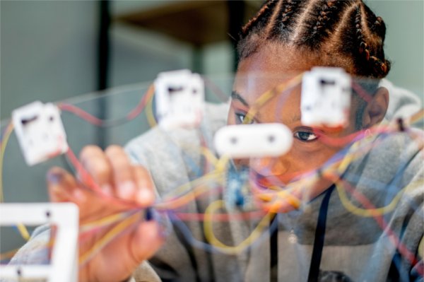 Close-up of a student concentrating while interacting with colorful wires. 