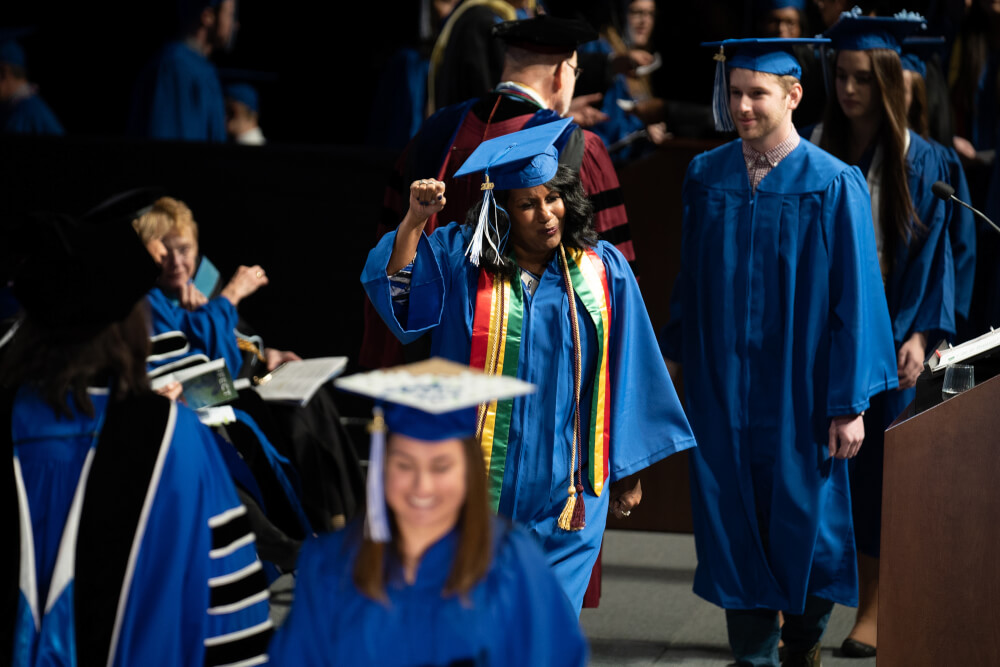 student walking to get diploma, excited with fist in air